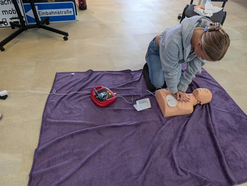 Teilnehmerin übt die Herzdruckmassage an einer Übungspuppe mit AED-Trainer
