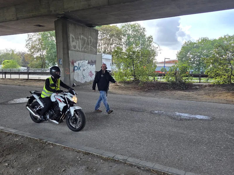 Fahrlehrer begleitet eine Fahrschülerin auf dem Motorrad per Funk auf dem Übungsgelände