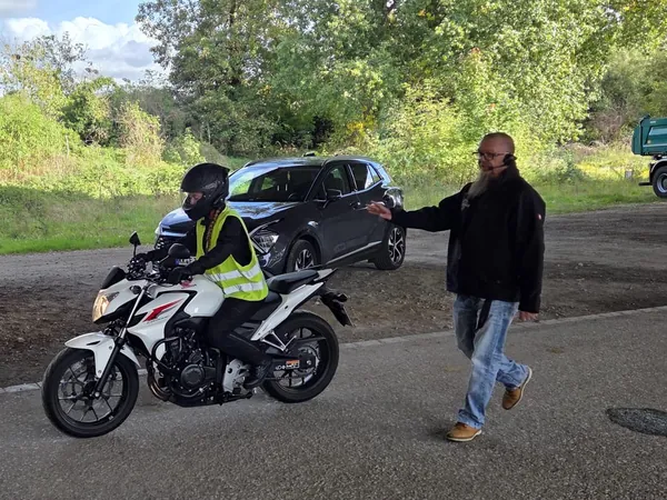 Fahrschülerin übt auf dem Motorrad, der Fahrlehrer gibt per Funk Anweisungen